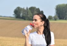 생명체에 중요한 물의 역할 a woman standing in a field drinking from a bottle