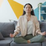 변화하는 정신건강 트렌드, ‘마음 챙김’이 일상 속으로 Woman meditating on couch with headphones on