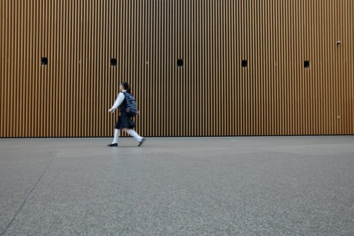 woman in uniform walkin on gray concrete pavement during daytime