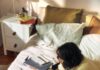 바쁜 직장인, 작은 변화로 건강 챙기기…“책상 앞 루틴이 답이다” Woman working on laptop on bed with snacks and books.