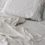 수면의 질 높이기, 일상에서 실천할 수 있는 건강 루틴 주목받아 A rumpled white duvet and pillows on a bed.