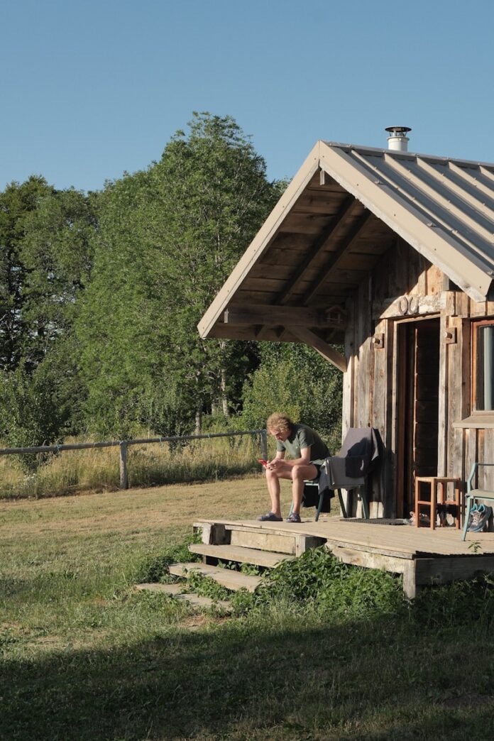 Man sitting on rustic cabin porch in nature.
