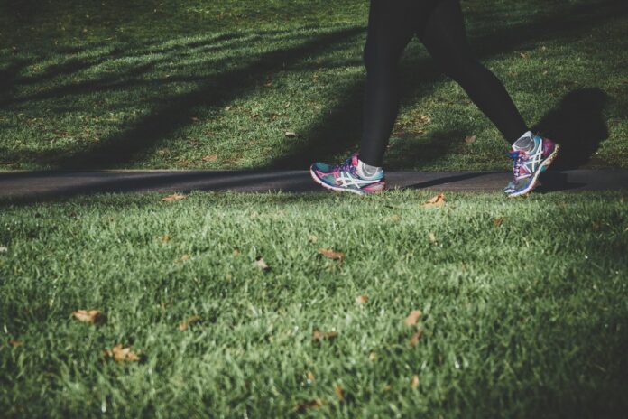 Photo by Arek Adeoye shallow focus photography of person walking on road between grass